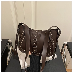 Close-up of vintage brown leather shoulder bag featuring silver rivets and eyelet strap