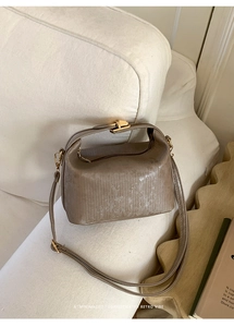 Detail showing retro brown leather texture and gold metal clasp of a small square bag