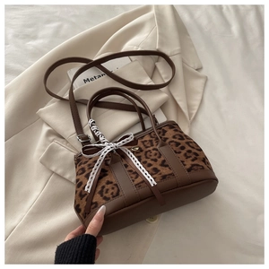 Détail du sac à main léopard avec nœud en dentelle blanche et bandoulière en cuir