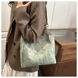 Detail of light green tote bag with moon star embossing and gold chain shoulder strap