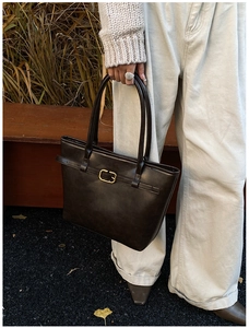 Close-up of matte brown leather tote with a gold square buckle and textured finish