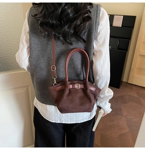 Detail of brown vintage suede bucket bag with gold buckle and adjustable strap