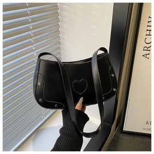 Detail showing the black leather surface with heart patch and silver metal rivets on bag