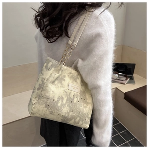 Detail of printed canvas tote bag featuring gold chain strap and moon star patterns