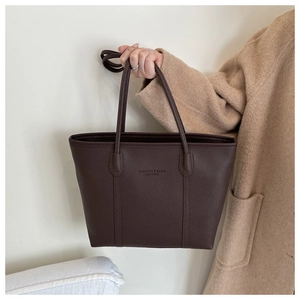 Close-up of deep brown lychee grain leather tote bag with elegant embossed text detail