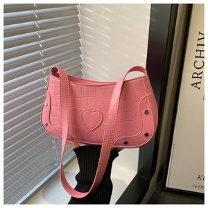 Close-up of pink crocodile texture handbag with heart patch and silver metal rivets