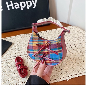Detail of checkered hobo bag with red leather bows, lace handle, and long shoulder strap