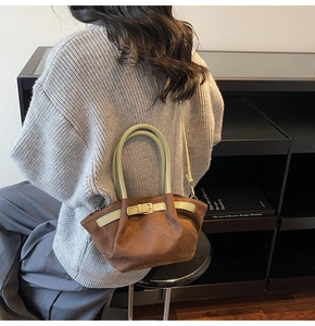 Detail view of suede bucket bag with contrasting green handles and gold buckle