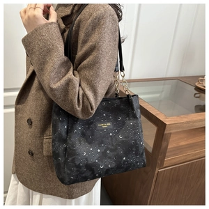Detail of star and moon printed canvas tote bag with chain strap on a model shoulder