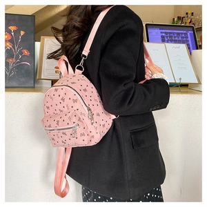 Dettaglio di mini zaino in velluto rosa con fiocchi neri indossato da modella