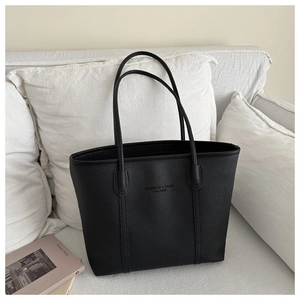Detailed macro view of litchi texture synthetic leather and embossed logo on black tote