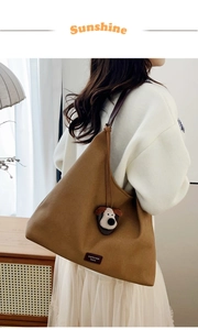 Detail of brown suede tote bag with a cute plush puppy pendant charm accessory