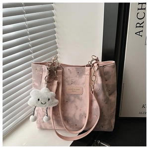 Detail of pink canvas tote bag with star patterns and fluffy cloud charm accessory