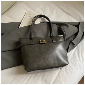 Detail of dark grey matte tote bag with vintage gold buckle on a minimalist office background