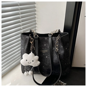 Detail of black star moon tote bag with gold chain handles and cloud charm accessory