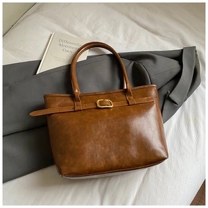 Detailed view of the brown vintage tote bag featuring a gold buckle and premium leather texture