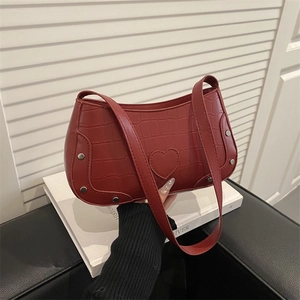 Red crocodile texture shoulder bag with heart patch and silver rivets on a white background