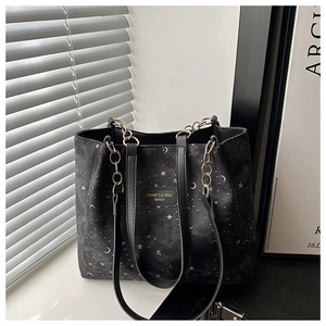 Detail of black canvas tote bag with silver star and moon patterns and gold chain