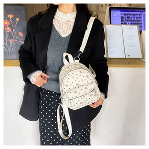 Dettaglio mini zaino in velluto beige con motivi di cuori e fiocchi marroni