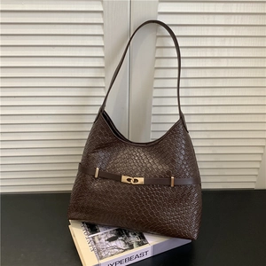 Sac hobo tressé marron foncé vintage avec boucle dorée sur des magazines de mode