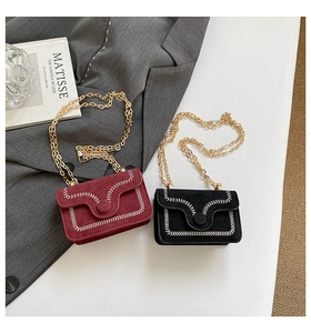Close-up of suede crossbody bags with decorative contrast hand-stitching and gold chain