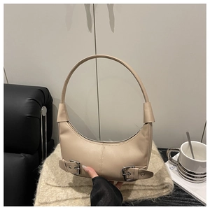 Close-up of beige hobo bag with silver buckle accents on a soft leather background