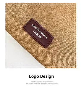 Close-up of leather logo patch and textured grain fabric on a brown tote bag
