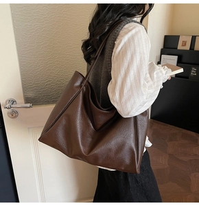 Detailed view of the dark brown leather tote bag texture and long shoulder strap design