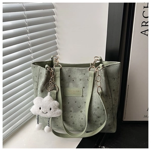 Detail of light green tote bag featuring star and moon prints with cloud charm
