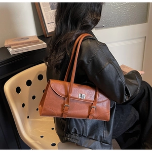Brown retro baguette shoulder bag with double strap details worn by a model in leather jacket
