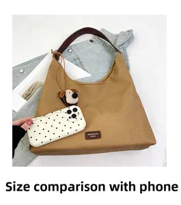Canvas tote bag size comparison with smartphone featuring leather straps and dog charm
