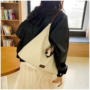 Detail of minimalist beige canvas tote bag with brown leather strap and plush dog charm