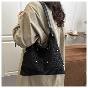 Dettaglio della borsa leopardata con borchie dorate indossata in una stanza dallo stile minimal