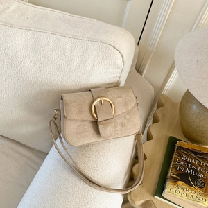 Vintage light brown suede messenger bag with gold ring buckle on a textured sofa