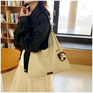 Detail of off-white tote bag with a cartoon puppy pendant and leather logo tag