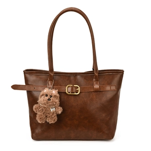 Retro dark brown leather tote bag with a cute dog plush charm on a clean white background