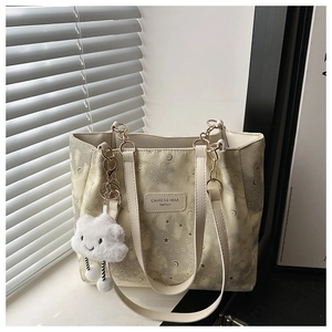 Close-up of beige canvas tote with star moon prints and gold chain metal handles