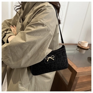 Detail of black leopard print suede underarm bag featuring a golden bow metal buckle