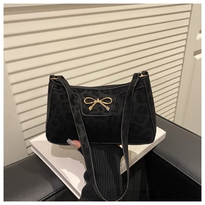 Detail of leopard print underarm bag with elegant gold bow buckle on black fabric