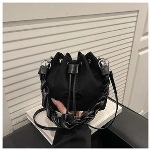 Close-up of black suede bucket bag with woven handle and drawstring closure detail