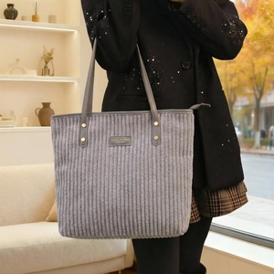 Detailed macro view of gray corduroy tote bag with leather badge and golden metal rivets