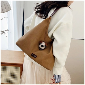 Detailed close-up of a brown canvas tote bag with a cartoon dog pendant on a leather strap