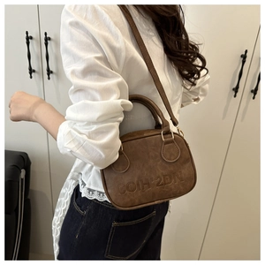 Detailed shot of retro brown leather handbag with embossed text and gold-tone hardware
