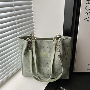 Green canvas tote bag with embroidered moon stars and chain straps in a bright room