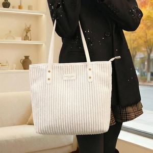 Detail showing white corduroy tote bag texture and fashion leather brand label