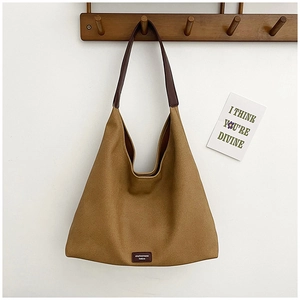 Detail of khaki canvas hobo bag with dark brown leather trim on a wooden hanger