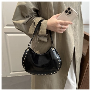 Détail du sac demi-lune en cuir verni noir avec des clous ronds dorés décoratifs