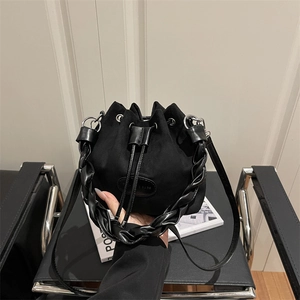 Retro black suede drawstring bucket bag featuring a unique braided leather top handle