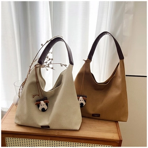 Detailed view of casual hobo tote bags in beige and brown with plush dog pendants
