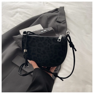 Detail of black leopard print crossbody bag with silver letter beads on blazer